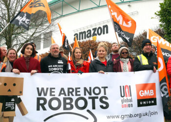 Εργαζόμενοι διαδαηλώνουν έξώ από κτήριο της Amazon με πανό που γράφει "Δεν είμαστε ρομπότ"